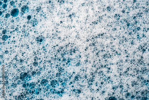 Background and pattern. White soap foam with bubbles, texture on blue tile background.