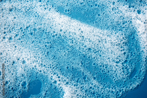 Background and pattern. White soap foam with bubbles, texture on blue tile background.