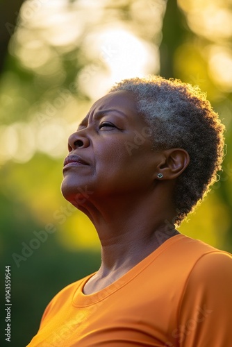 thoughtful moment of african american old woman enjoying nature's tranquility at sunset. meditation and fitness, health, wellness. active aging, healthy lifestyle, senior activity