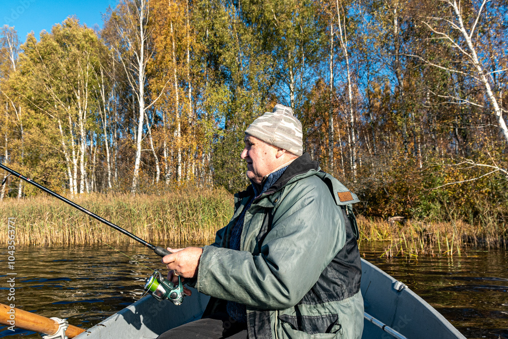 fisherman in a boat, colorful background of trees on the shore of the lake fisherman in a boat, colorful background of trees on the shore of the lake