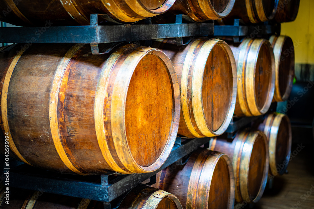Wooden barrels with metal rings, in a wine cellar ,Brown wooden wine beer barrel stacked background Wooden barrels with metal rings, in a wine cellar ,Brown wooden wine beer barrel stacked background