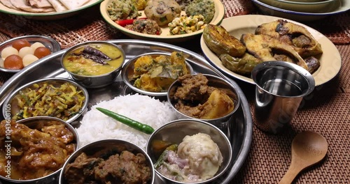 Bengali style thali spread verity cuisine hilsa fish vegetable beef mutton egg curry fry vorta mashed chicken liver sweet yogurt side dish served on rustic metal tin stainless steel plate small bowls photo