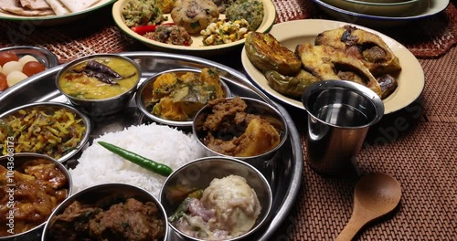 Bengali style thali spread verity cuisine hilsa fish vegetable beef mutton egg curry fry vorta mashed chicken liver sweet yogurt side dish served on rustic metal tin stainless steel plate small bowls