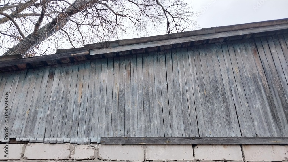 Naklejka premium a section of a building with a corrugated metal wall. The metal appears weathered and has a grayish color. Below the metal wall, there is a row of concrete blocks forming the base of the structure