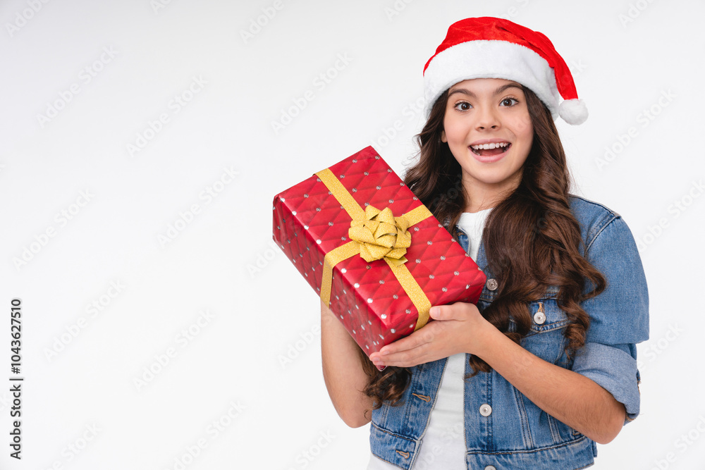 Cheerful surprised caucasian little teen girl in Santa`s red hat holding her Christmas gift present, celebrating New Year isolated over white background Cheerful surprised caucasian little teen girl in Santa`s red hat holding her Christmas gift present, celebrating New Year isolated over white background