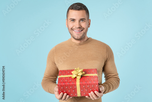 Photo portrait of happy cheerful man holding present box wrapped ribbon on birthday party anniversary christmas valentines day 8 march isolated pastel blue color background photo