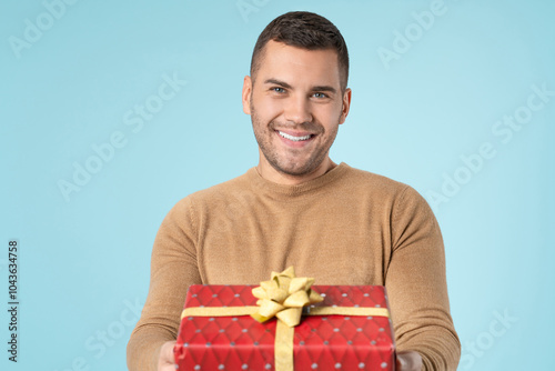 Close up portrait of happy cheerful man holding present box wrapped ribbon on birthday party anniversary Christmas valentines day 8 march isolated pastel blue color background