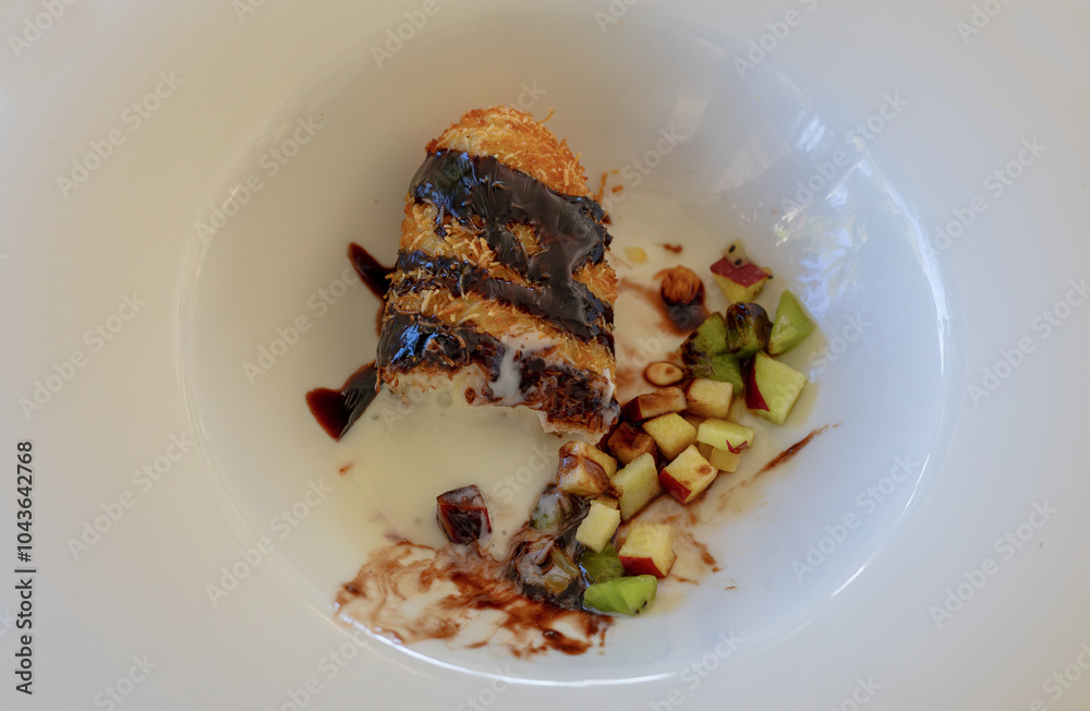 Fried ice cream with shredded wheat, fruit pieces and chocolate sauce on a white porcelain plate (Hot ice cream)