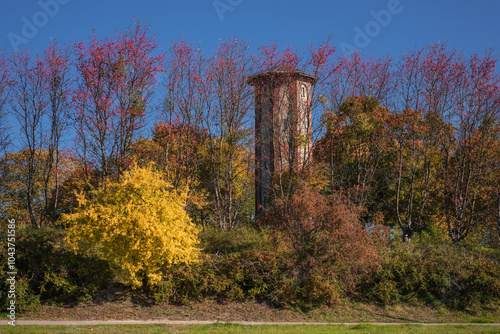 AUTUMN IN CITY - A historic water tower against the background of colorful trees photo