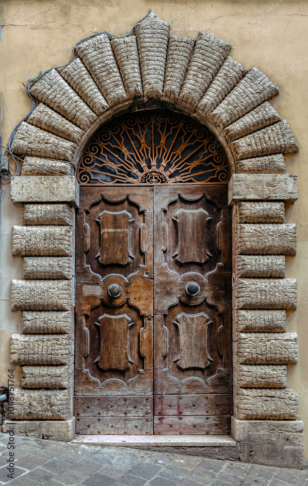 The beautifully crafted medieval entrance door in Tuscany, Italy showcasing intricate stonework and wooden details