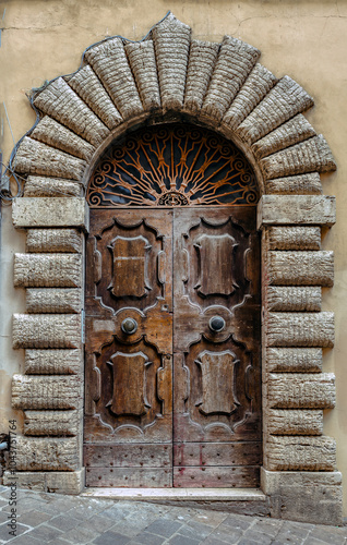 Obraz na płótnie The beautifully crafted medieval entrance door in Tuscany, Italy showcasing intricate stonework and wooden details w salonie