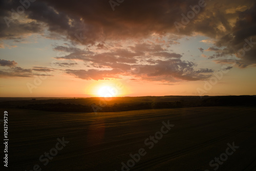 Aerial landscape view of yellow cultivated agricultural field with ripe wheat on vibrant summer evening