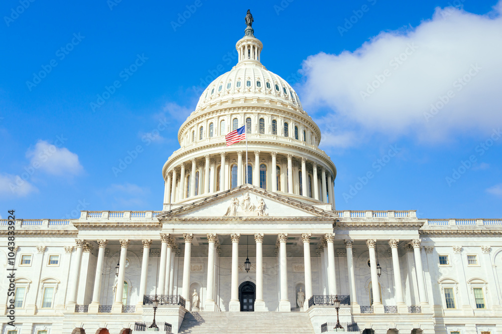 Obraz premium United States Capitol building with American flag over blue sky background, Washington DC