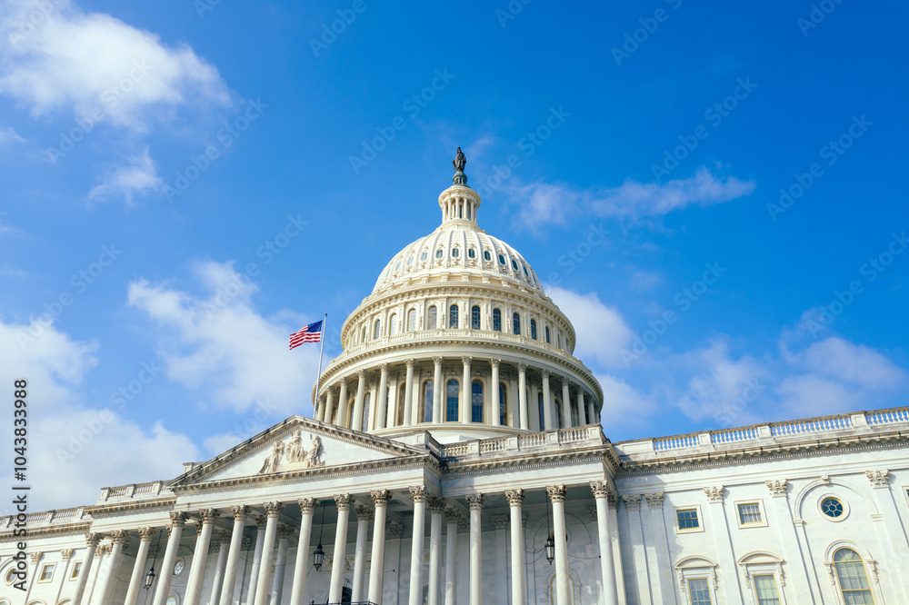 Obraz premium United States Capitol building with American flag over blue sky background, Washington DC