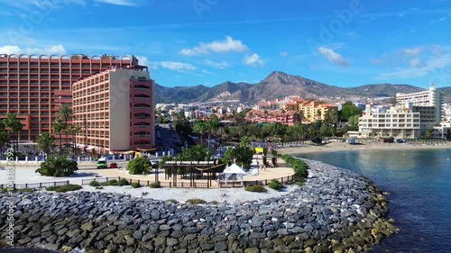 Aerial drone view of the Benalmadena coast overlooking the Sunset Beach hotel, coastline, residential sector, beach and mountains in the background.