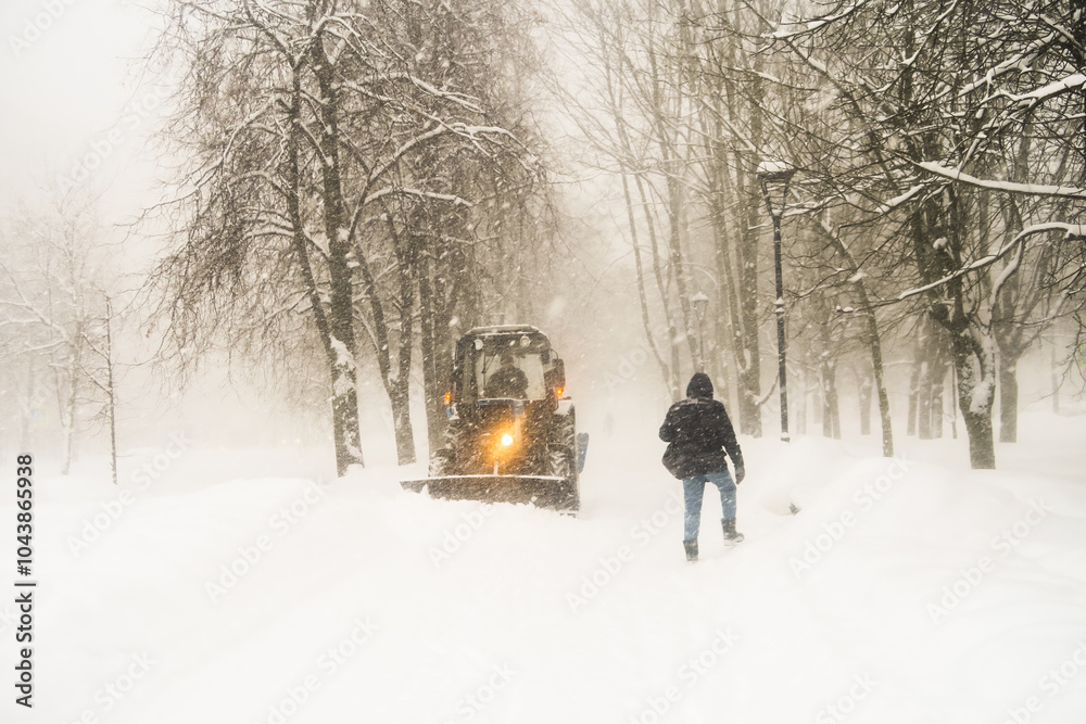Black and white image of a heavy snowfall. Walking with a dog in bad weather on a city street. Snow storm in the city. Black and white image of a heavy snowfall. Walking with a dog in bad weather on a city street. Snow storm in the city.