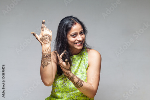 A joyful Indian woman showcasing her beautiful henna design in a dancing posture, captured during the Karva Chauth festival, symbolizes tradition and beauty.	
 photo