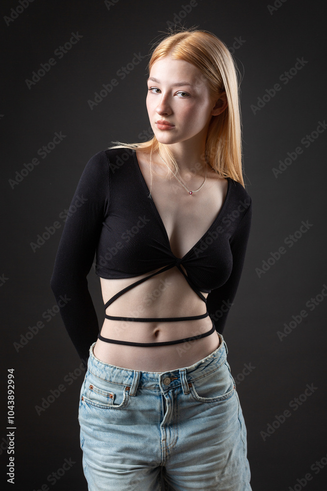 Portrait of a blonde woman with freckles in a sexy top and denim shorts in a studio. Portrait of a blonde woman with freckles in a sexy top and denim shorts in a studio.