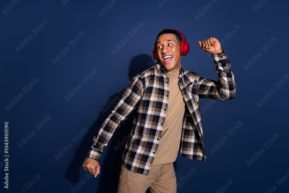 Photo of funky cool guy dressed plaid shirt earphones having fun looking emtpy space isolated blue color background
