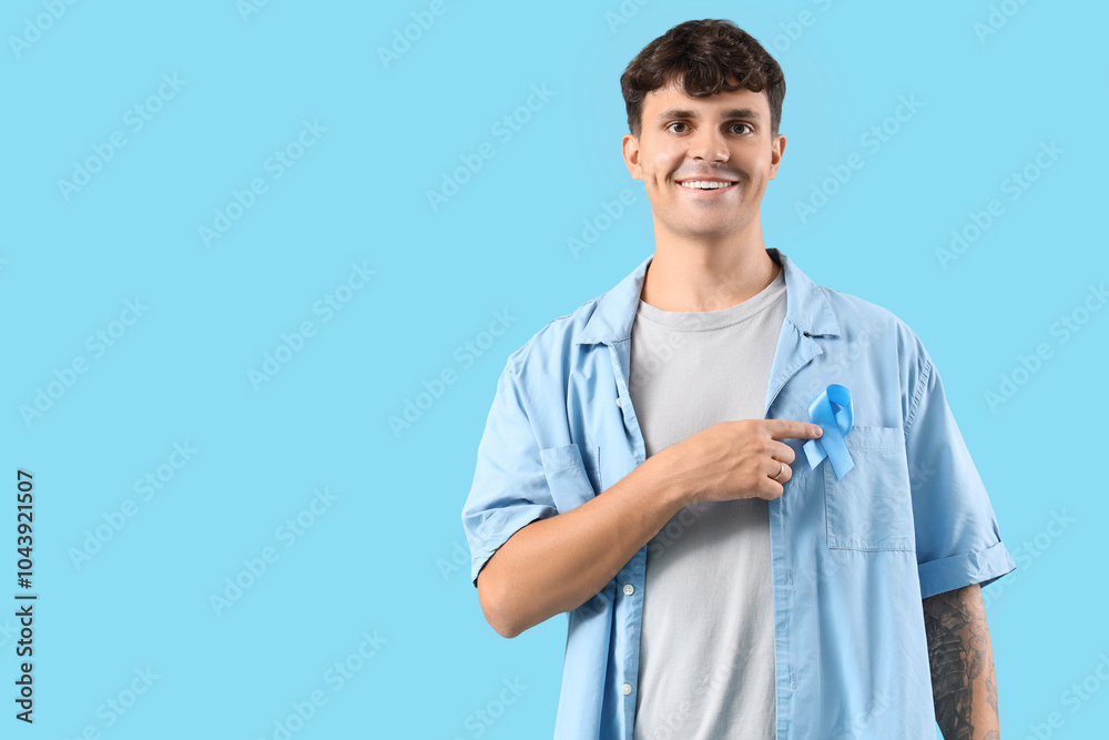 Young man with blue ribbon on color background. Prostate cancer awareness concept Young man with blue ribbon on color background. Prostate cancer awareness concept