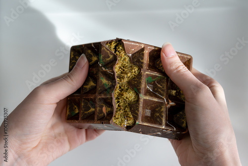 Dubai chocolate with pistachio, tahini and kadaif, chocolate broken in woman's hands