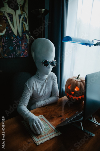 Wallpaper Mural Teenager in Halloween full-body freaky white costume with carved pumpkin laptop on table studying online Torontodigital.ca