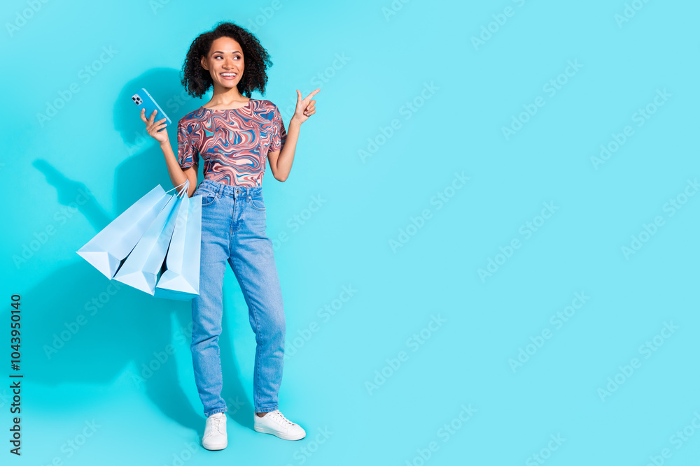 Full body photo of pretty young girl device shopping point empty space wear trendy colorful clothes isolated on aquamarine color background Full body photo of pretty young girl device shopping point empty space wear trendy colorful clothes isolated on aquamarine color background