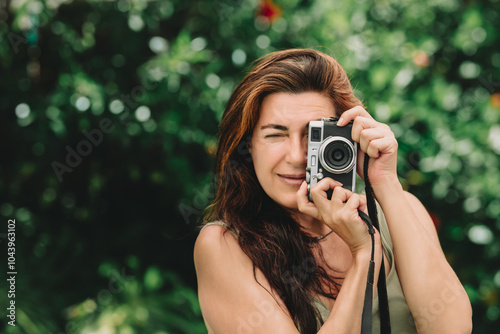 Woman capturing moments with a retro style camera outdoors photo