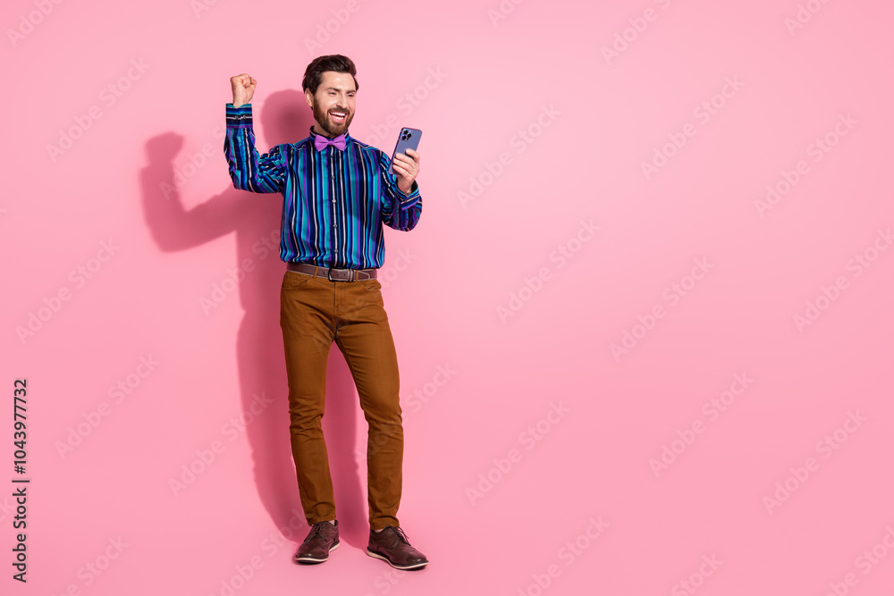 Full length photo of groomed glad positive elegant man wear trendy striped clothes empty space isolated on pink color background Full length photo of groomed glad positive elegant man wear trendy striped clothes empty space isolated on pink color background
