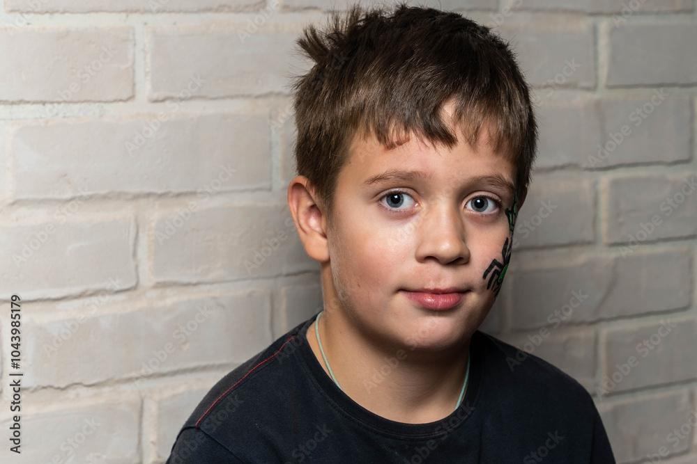 Boy with spider face painting posing near brick wall Boy with spider face painting posing near brick wall