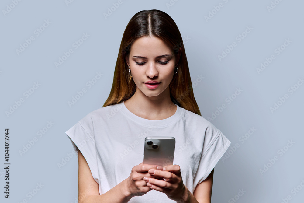 Young beautiful woman using smartphone on grey studio background Young beautiful woman using smartphone on grey studio background
