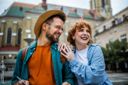 Young couple exploring the new city. Hugging and walking through the center. Wearing hats and backpacks.