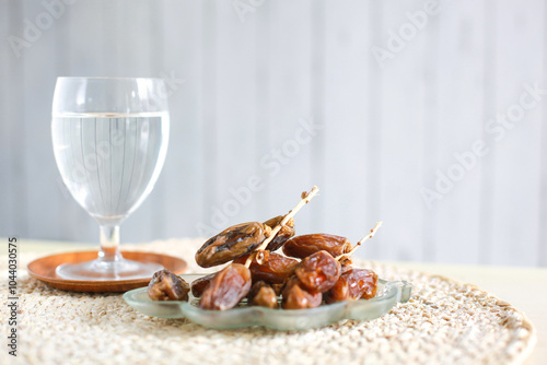 A glass of water and a plate of dates at iftar time photo