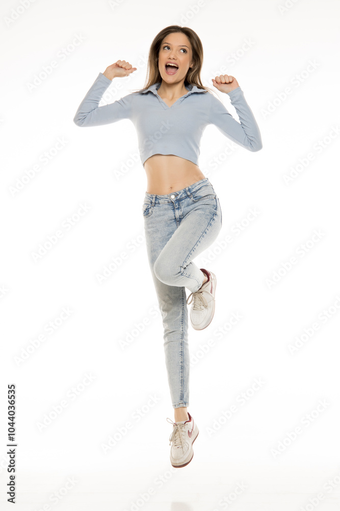 Beautiful young happy woman in a blue jeans and shirt jumping on a white studio background. Front view. Beautiful young happy woman in a blue jeans and shirt jumping on a white studio background. Front view.