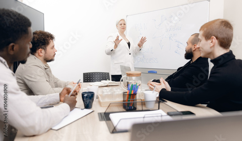 Colleagues of diverse ethnicities engaging in brainstorming session in office. focus on woman presenting on whiteboard with key topics like plan, result, and success highlighted photo