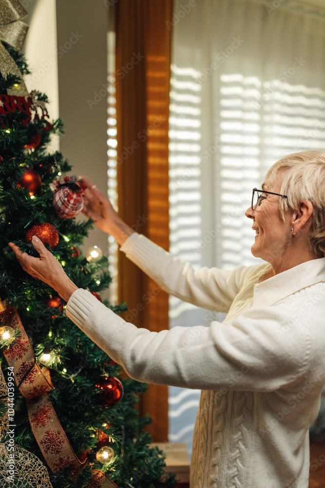 Senior woman decorating christmas tree at home Senior woman decorating christmas tree at home