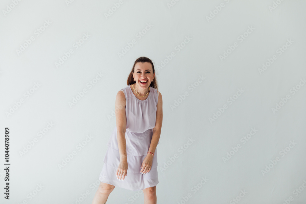 Beautiful brunette woman in light summer dress smiling at white wall Beautiful brunette woman in light summer dress smiling at white wall