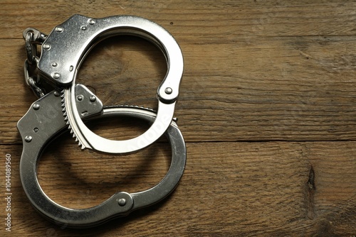 Classic chain handcuffs on wooden table, top view. Space for text