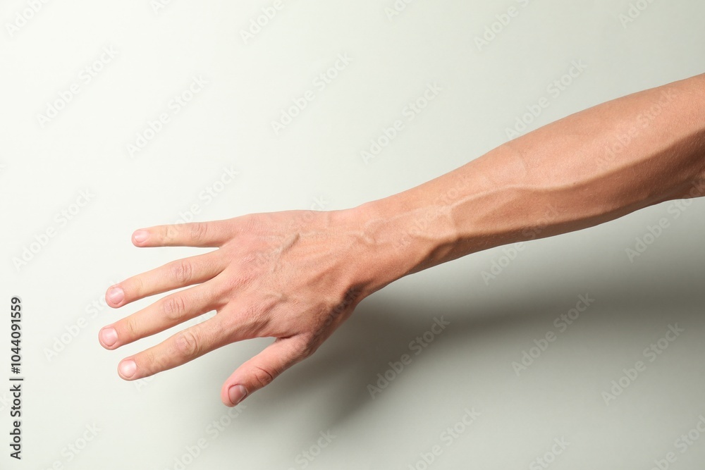 Man with bulging veins on his arm against light background, closeup Man with bulging veins on his arm against light background, closeup