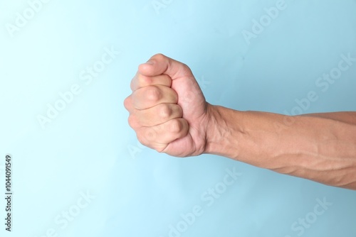 Man with bulging veins on his arm against light blue background, closeup