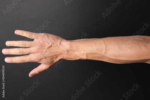 Obraz na plátně Man with bulging veins on his arm against black background, closeup