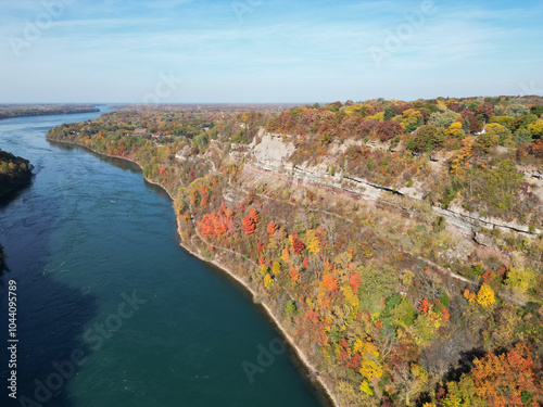 Aerial over the Niagara River and gorge between Lewiston, New York, United States and Ontario, Canada towards Lake Ontario. Shot during an autumn afternoon with colorful fall foliage trees in October.