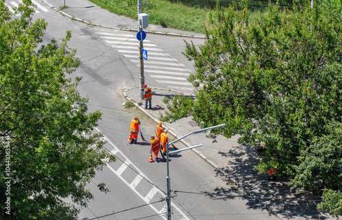 Municipal cleaners manually sweep the city roadway photo