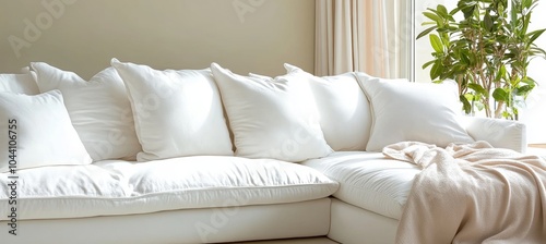 White sofa with muslin pillows and light brown blanket near a window with muslin curtains in room. photo