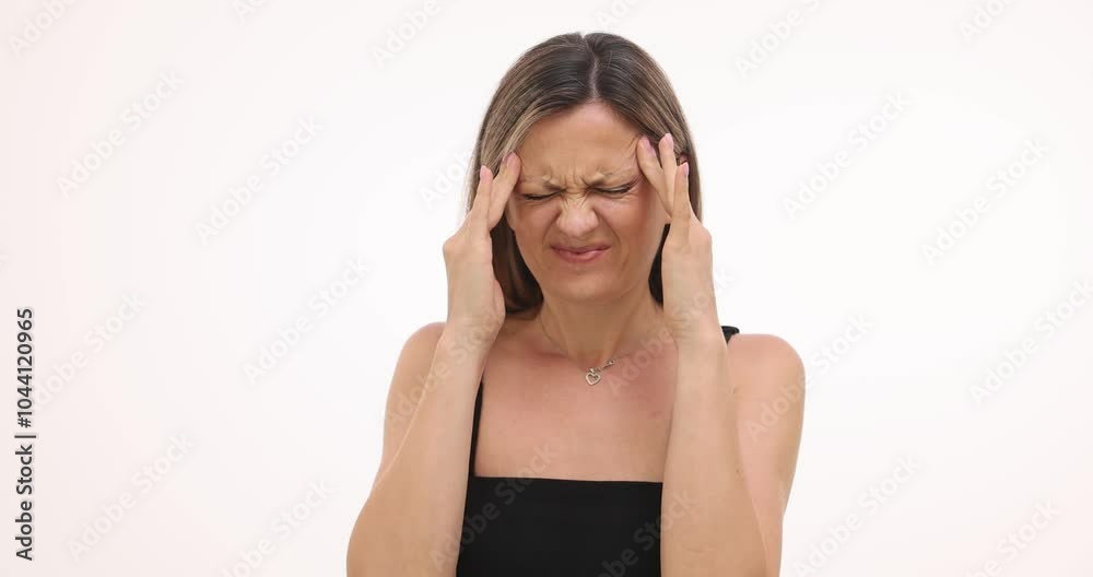 Young woman with pained expression massages temples on white background. Blonde female tries to relieve tension caused by headache slow motion Young woman with pained expression massages temples on white background. Blonde female tries to relieve tension caused by headache slow motion