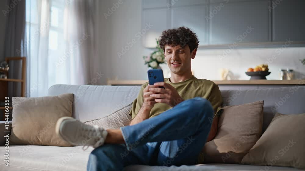 Smiling student browsing smartphone social networks application at cozy sofa