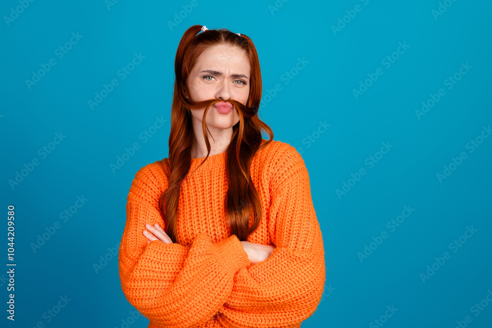 Fototapeta premium Photo of doubtful lovely girl orange knitwear sweater making tails fake mustache looking empty space isolated blue color background