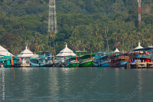 Landscape with several boats moored on a pier, next to some buildings on the island of Koh Chang, Thailand