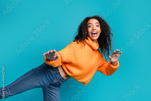 Photo of cheerful pretty teen lady dressed orange turtleneck dancing empty space isolated blue color background photo