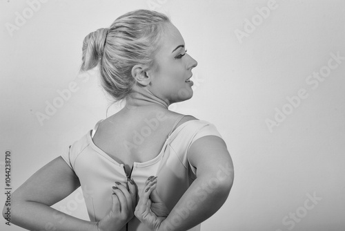 Woman struggling to close dress zipper at home